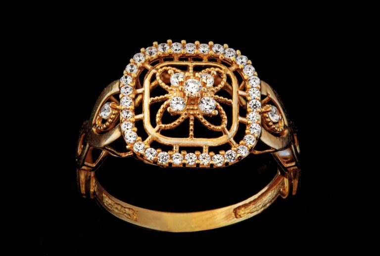 Luxurious gold ring adorned with glittering diamonds on a dark backdrop, showcasing elegance and craftsmanship.