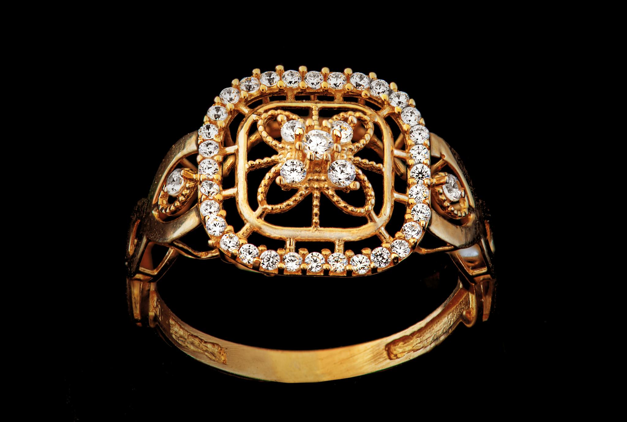 Luxurious gold ring adorned with glittering diamonds on a dark backdrop, showcasing elegance and craftsmanship.